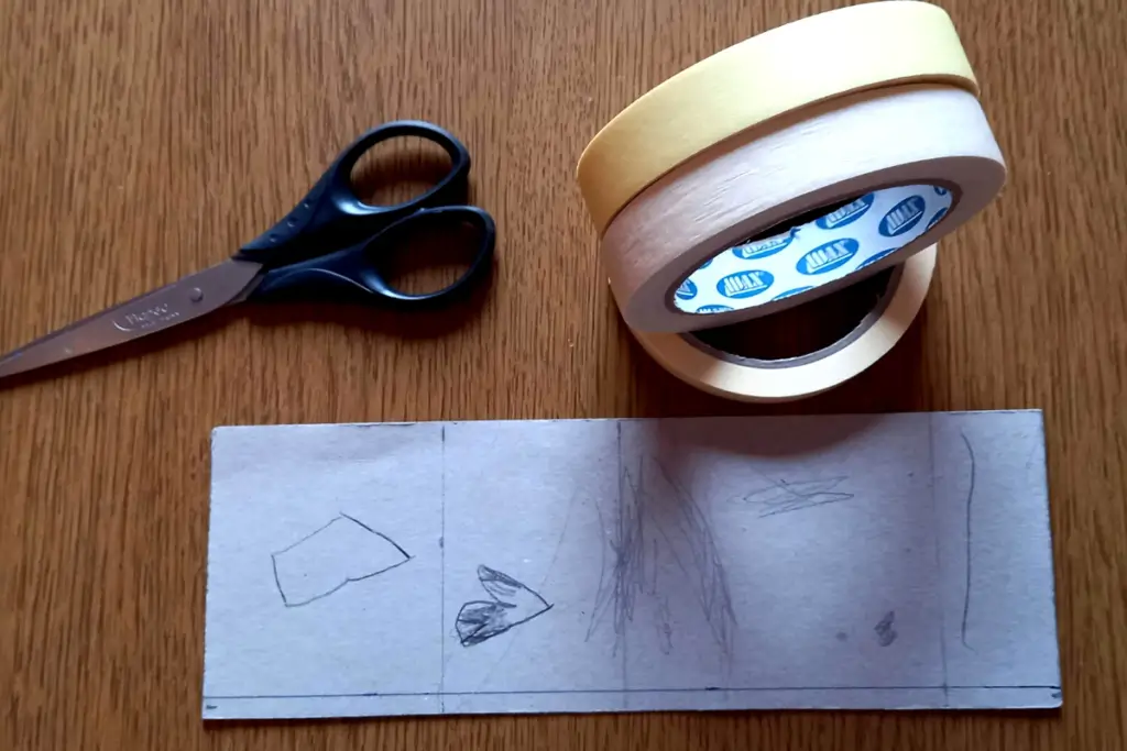 How to Paint Baby Room Wall 8 DIY craft setup with scissors, masking tape rolls, and marked cardboard template on wooden table