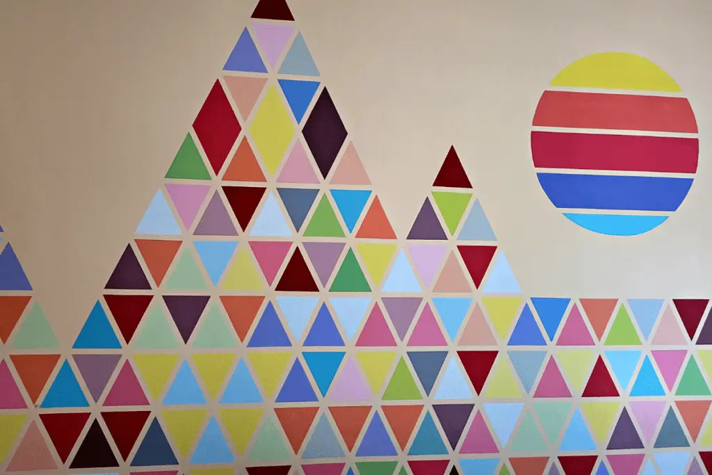 How to Paint Baby Room Wall 6 Abstract geometric wall art with colorful triangle mountains and a striped sun on a beige background