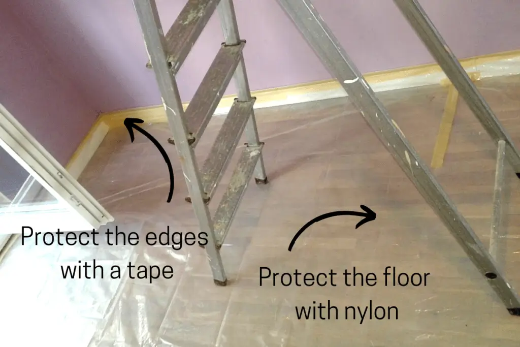 How to Paint Baby Room Wall 4 Ladder in a room prepped for painting; floor covered with plastic and baseboards masked with tape