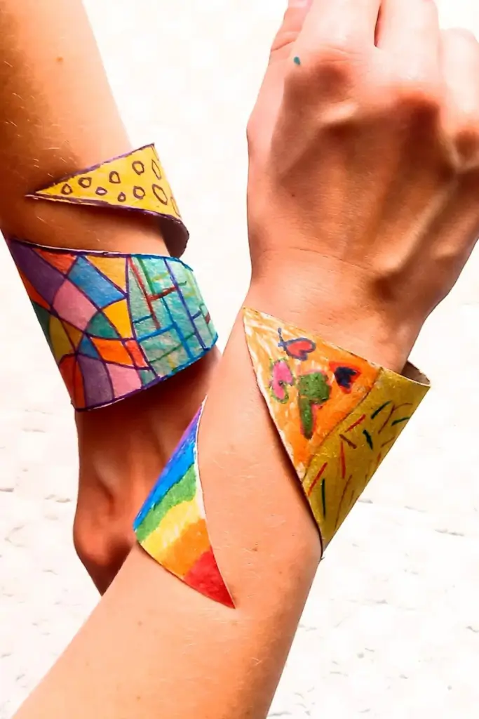 Toilet Paper Roll Bracelets: Crafts for Kids 2 DIY toilet paper roll cuff bracelets with colorful marker designs on wrists