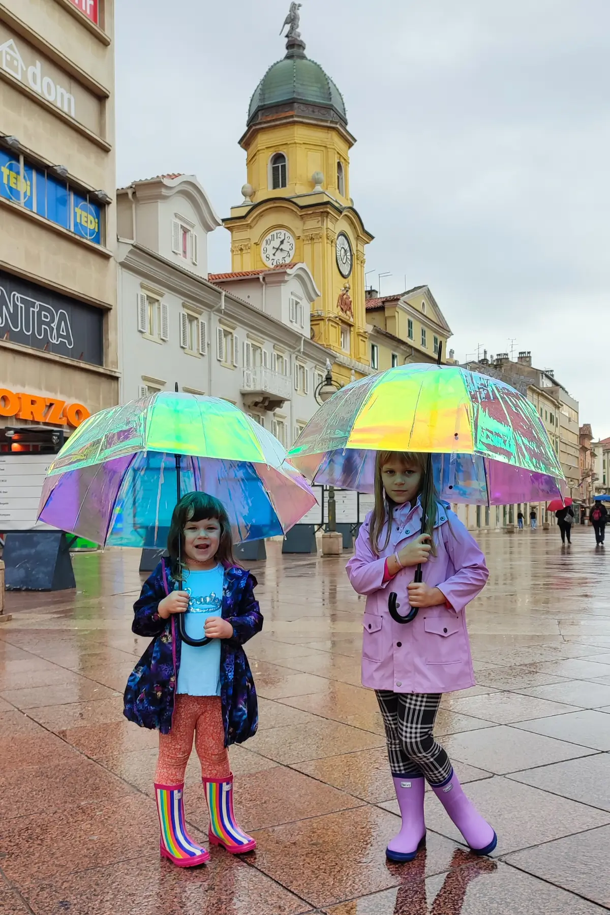 Non Toy Gifts for 1 Year Old - 25 Ideas From Moms 17 Two girls with iridescent umbrellas on a rainy day at Rijeka's Korzo near the yellow city clock tower