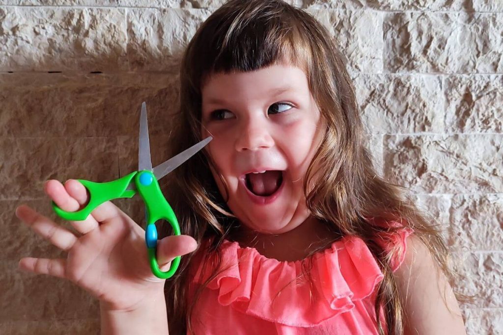 a child holding scissors and getting ready to do some cutting paper activities