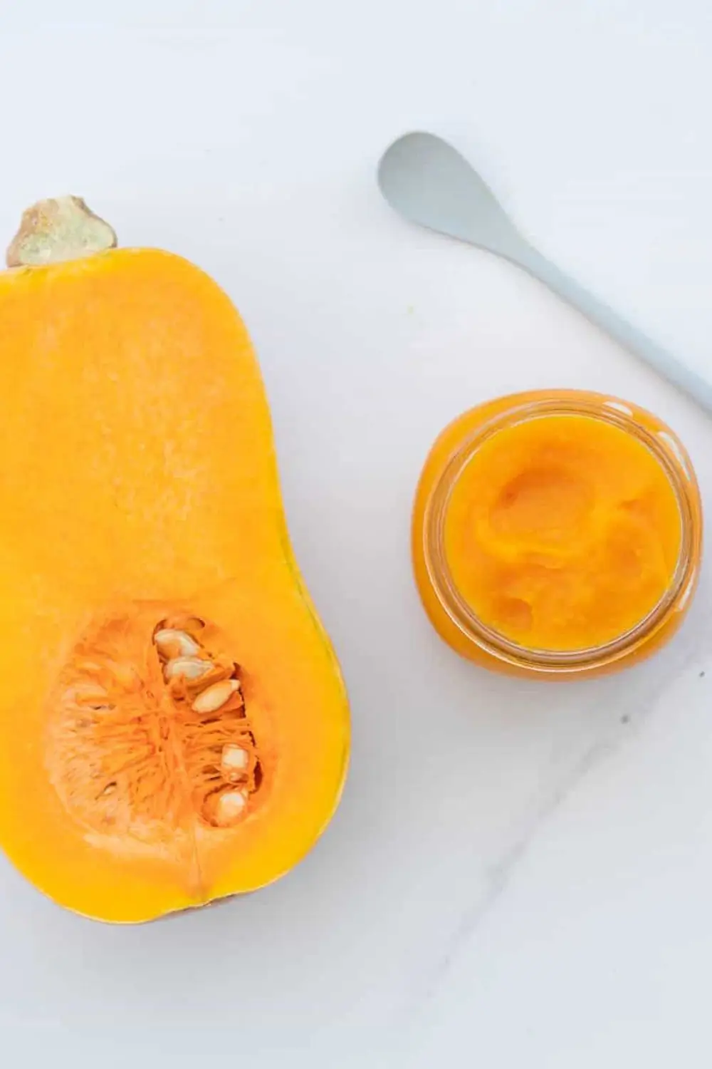 Butternut squash baby puree in jar with spoon and halved squash
